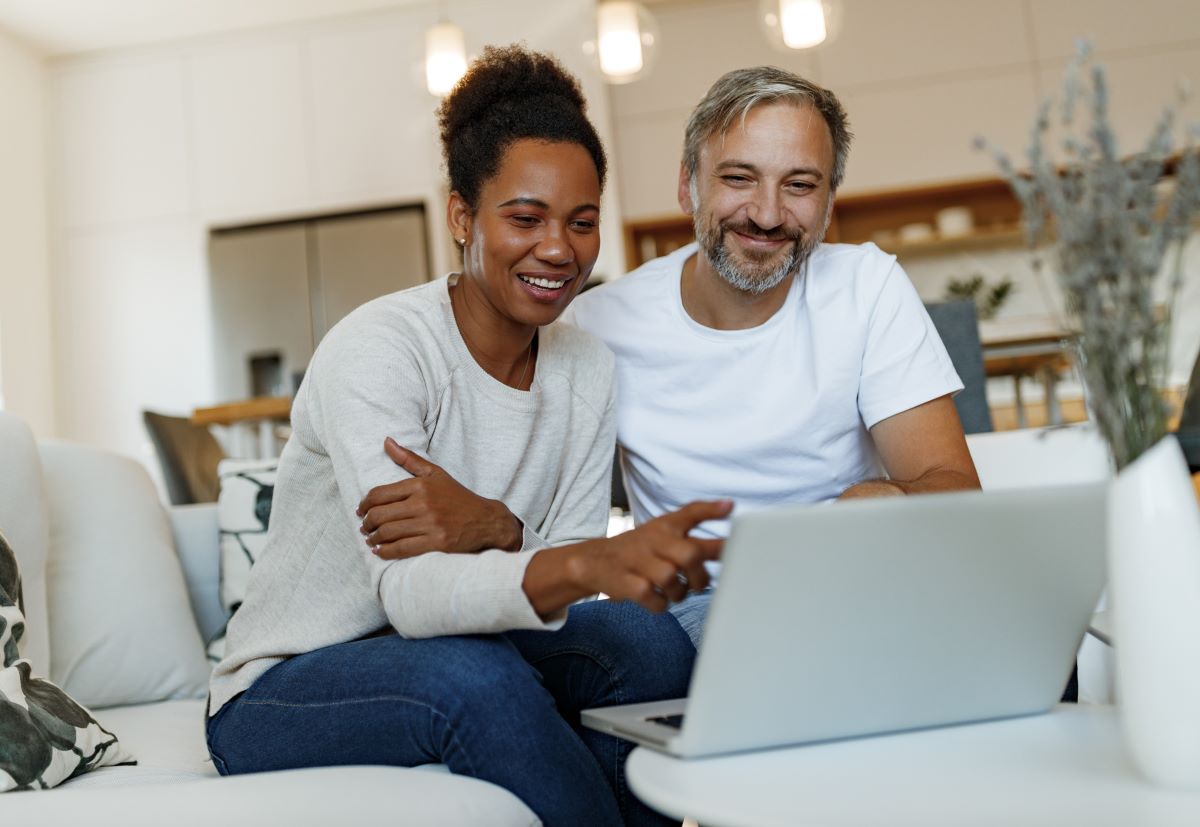 Couple looking at laptop sitting on a couch