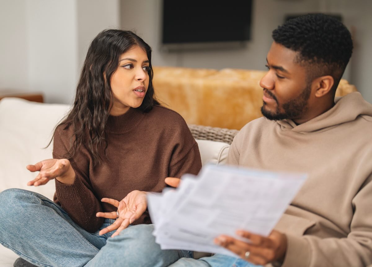 Two people engage in a discussion while reviewing documents in a cozy living room setting