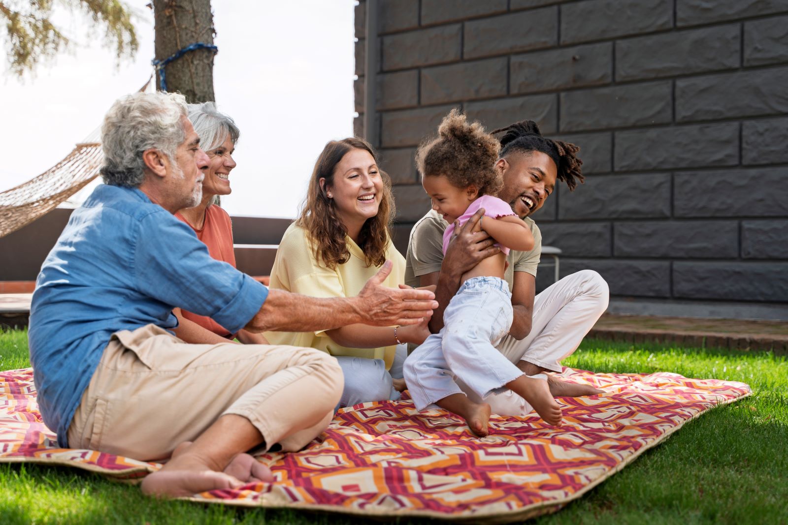 Family with grandparents playing with a child at their backyard