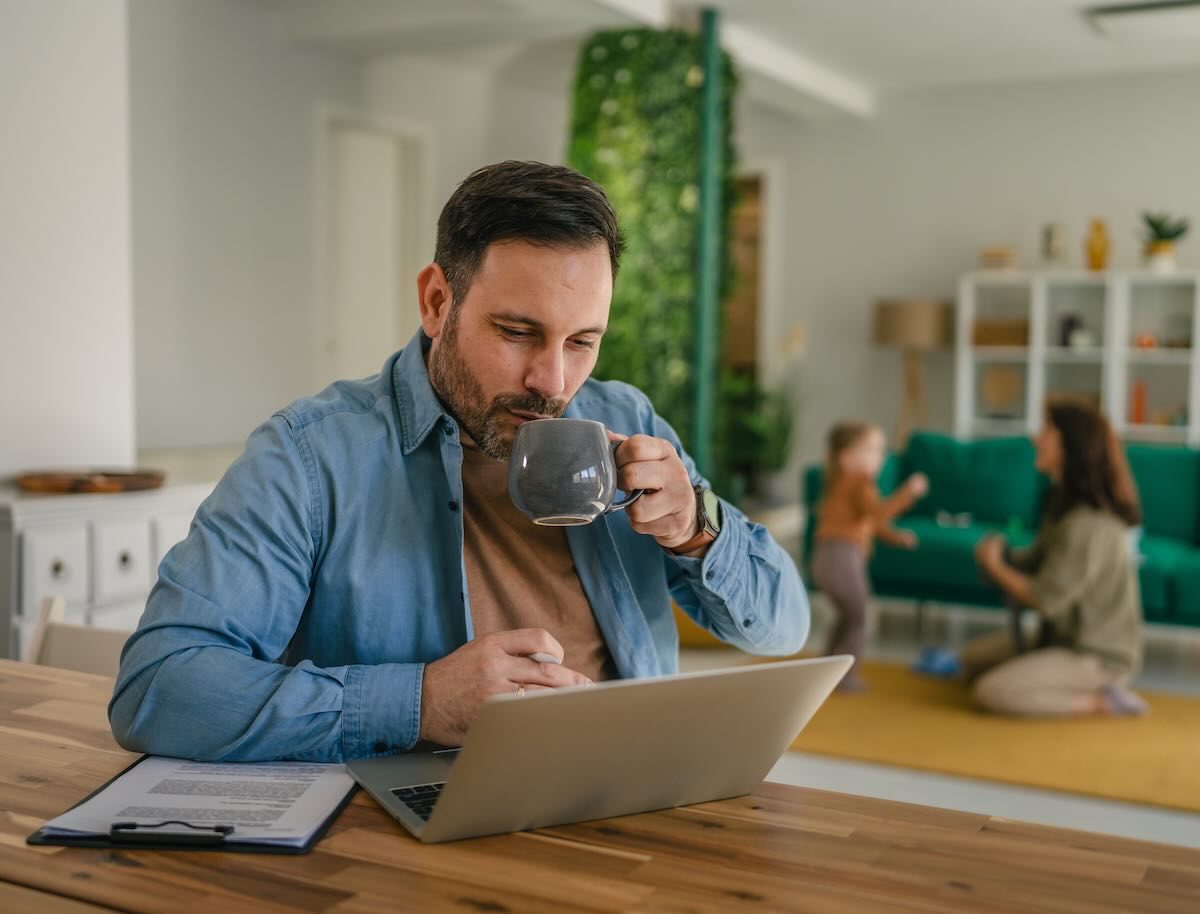 Man working from home drinking coffee with family 